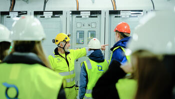 Energioperatør omviser ungdommer inne i kraftstasjon.